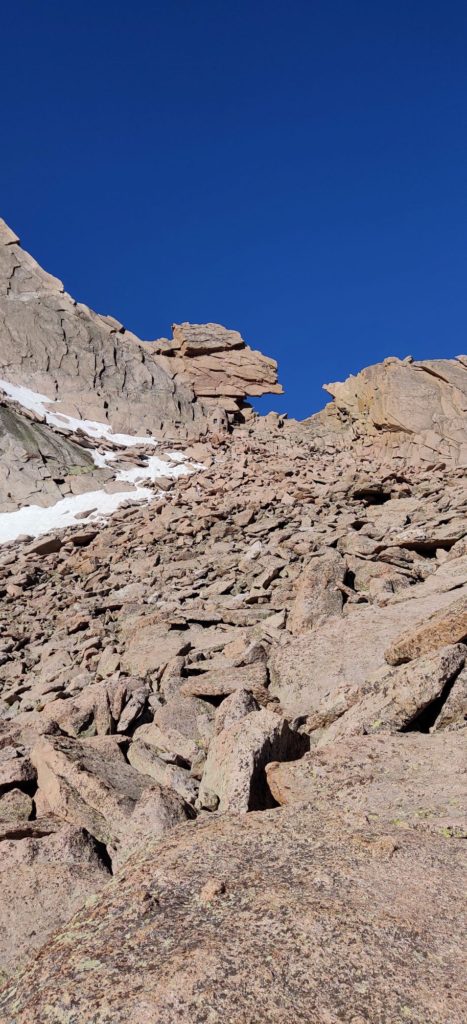 A keyhole shaped rock formation with snow on the top at Longs Peak
