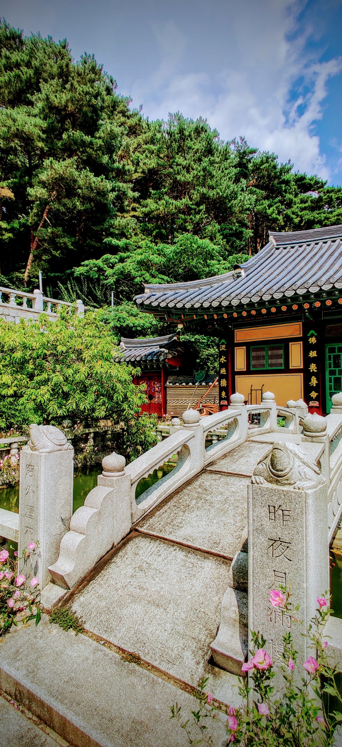 a stone bridge crosses a coy pond in front of a buddhist monk living quarters in a temple