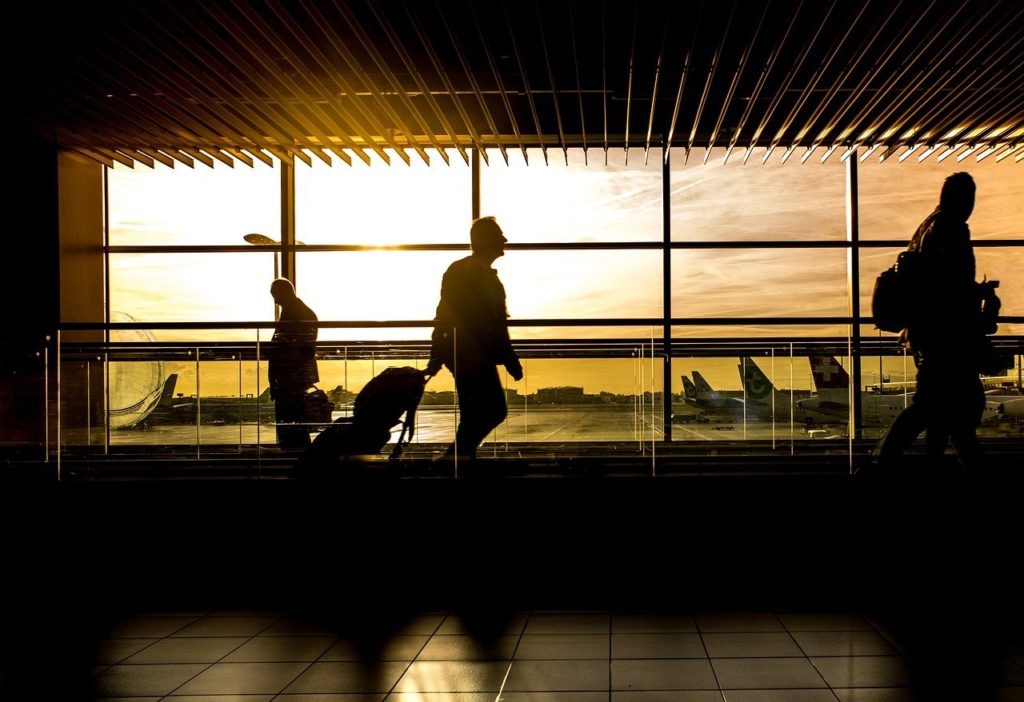 A silhouette of people with luggage in an airport as they PCS to Korea