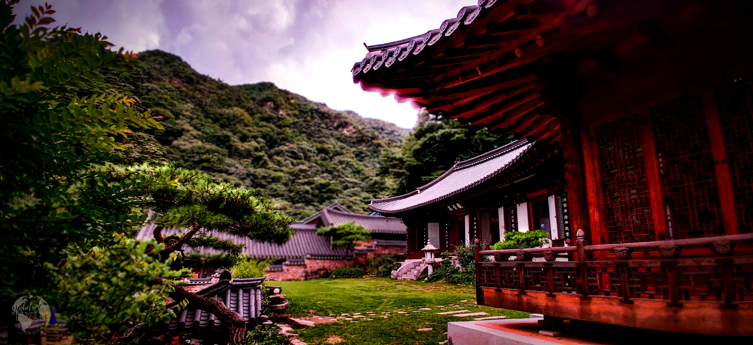 a dark and stormy sky sits behind a wooden buddhist temple in a mountain valley of south korea's mountains