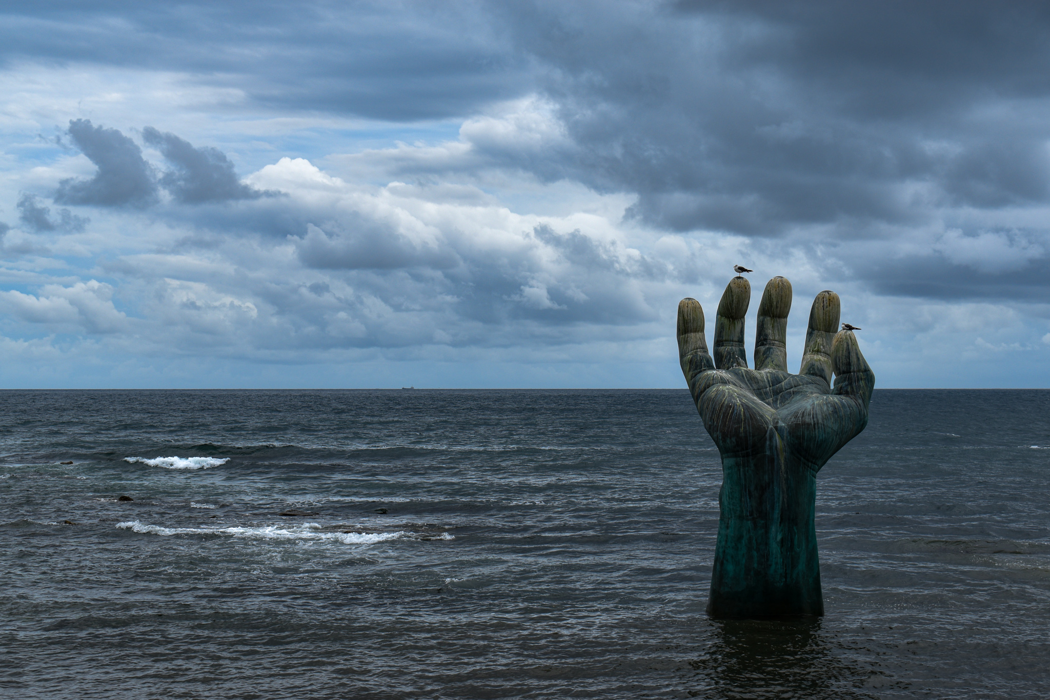 a hand sculpture in the middle of the ocean in south korea homigot hands of harmony pohang dark stormy ocean cloudy ominous sky