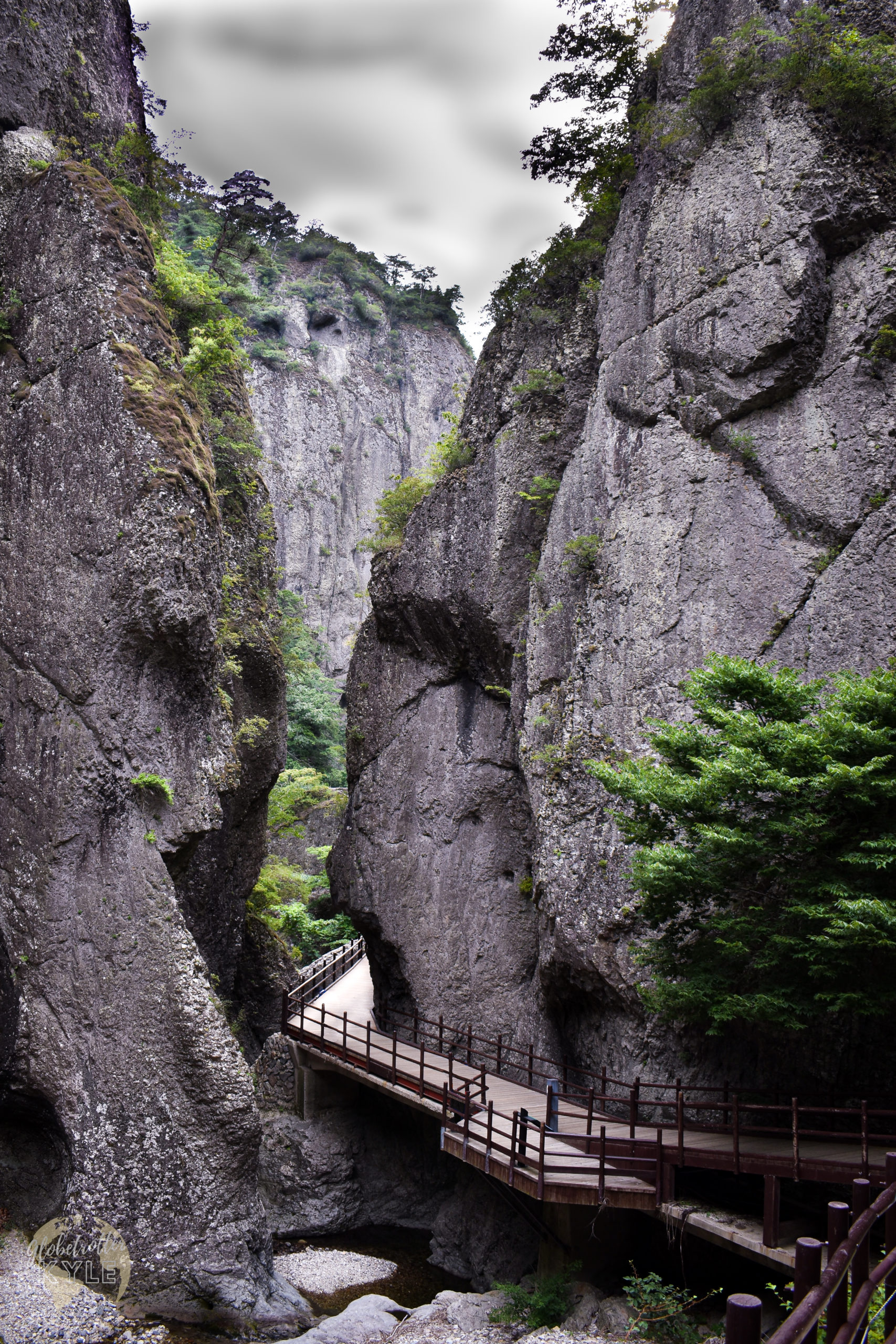 a walkway passes through a rocky canyon with trees on either side in south korea juwangsan national park