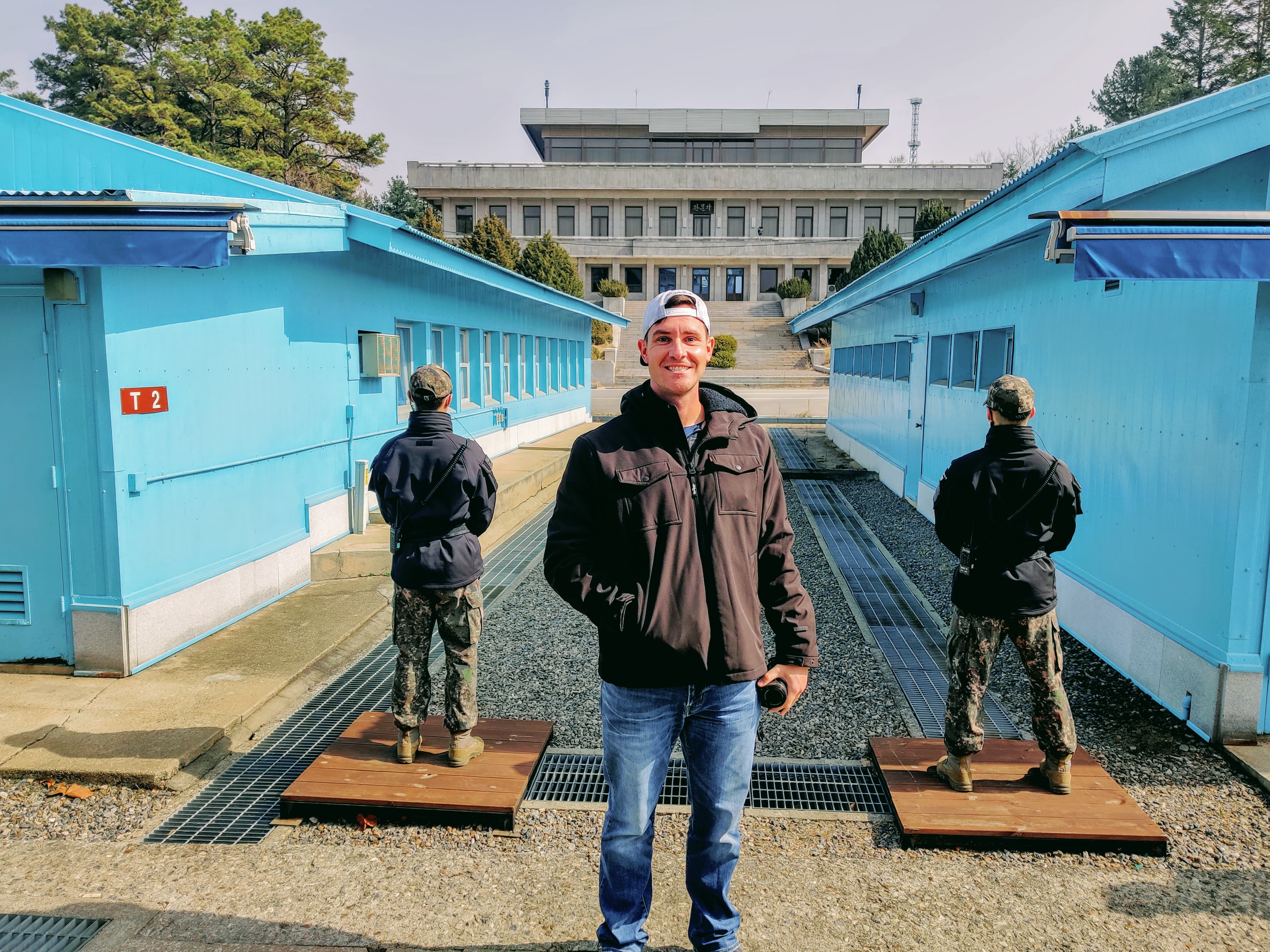A person standing in front of a group of blue buildings at the Korean DMZ