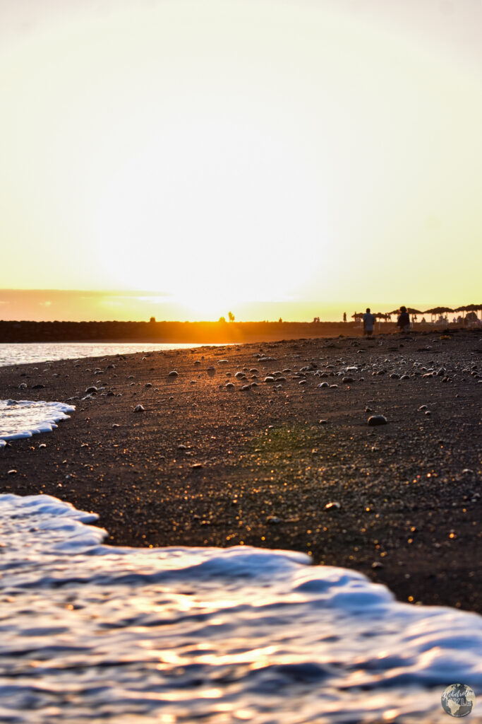 A black sand beach with waves and a sunset in Tenerife Canary Islands, one of the many what to do in Tenerife items