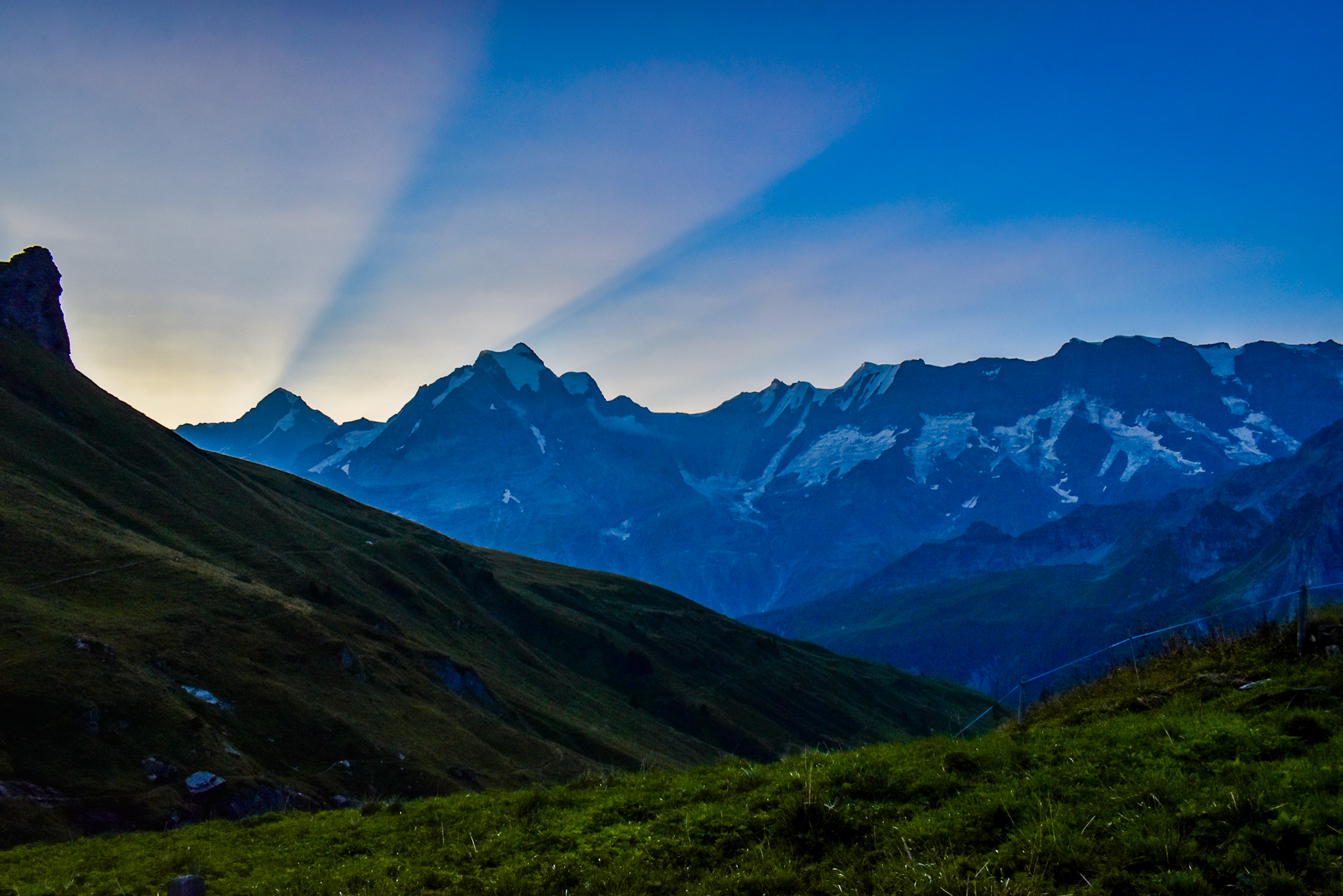 sun rays shine past a mountain ridge in Switzerland 