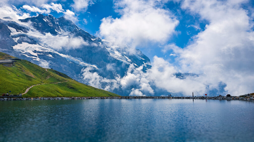 Fallbodensee, a high alpine lake reflects snowy mountains in the background, in Switzerland 